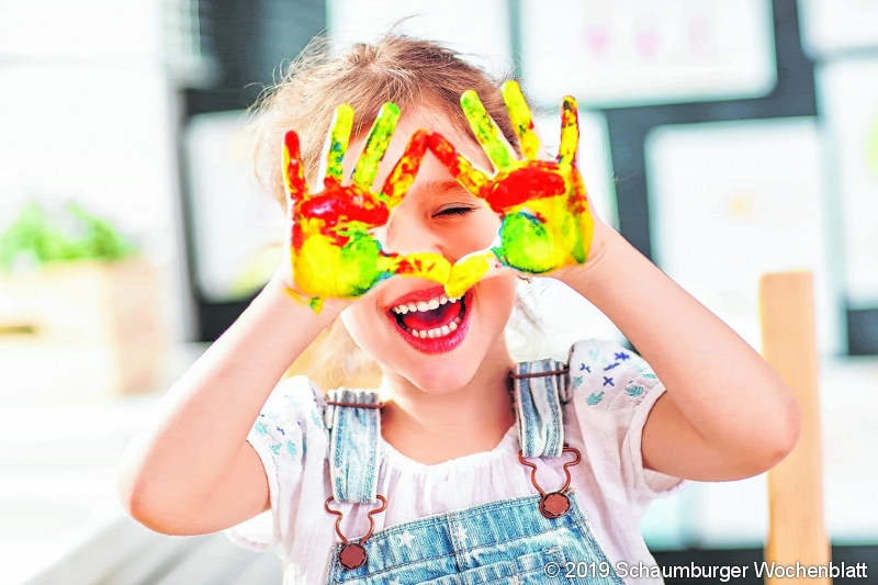happy funny child girl draws laughing shows hands dirty with paint