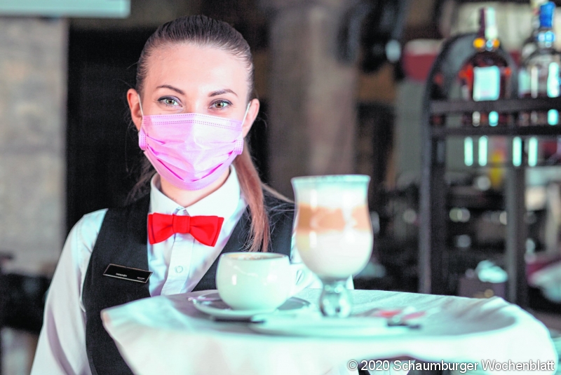 the waiter works in a restaurant in a medical mask