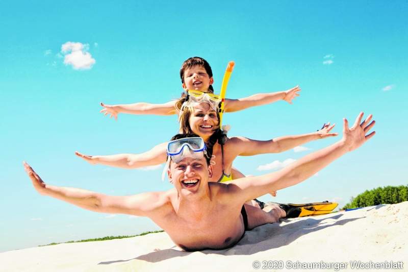 Portrait of cheerful couple and their son lying on sand and looking at camera