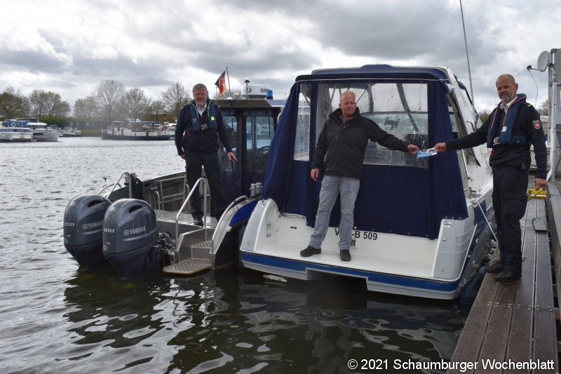 Polizeikommissar Bößmann und Polizeikommissar Fliege überreichen einem Sportbootfahrer den neuen Flyer.